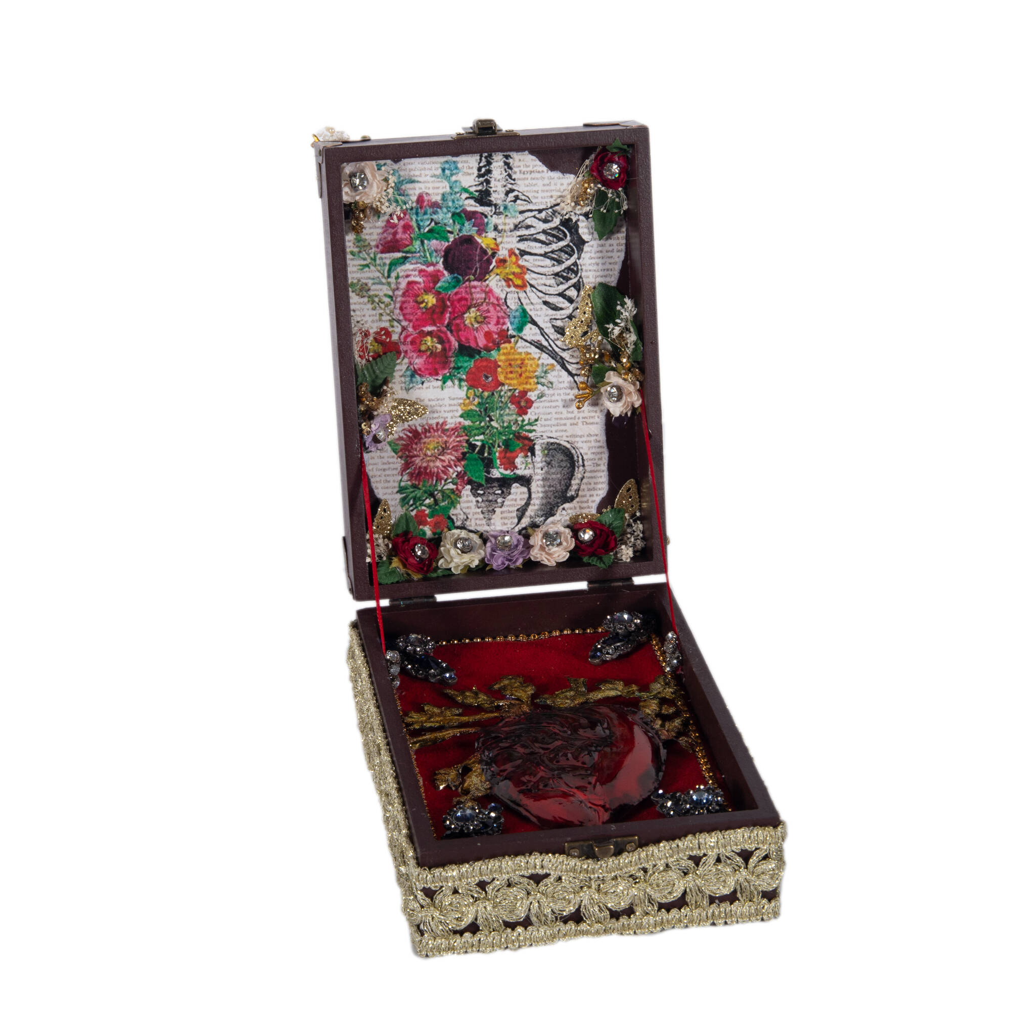 Open box that has a collage inside the lid with images of flowers and a human rib cage. Inside of box has a heart.